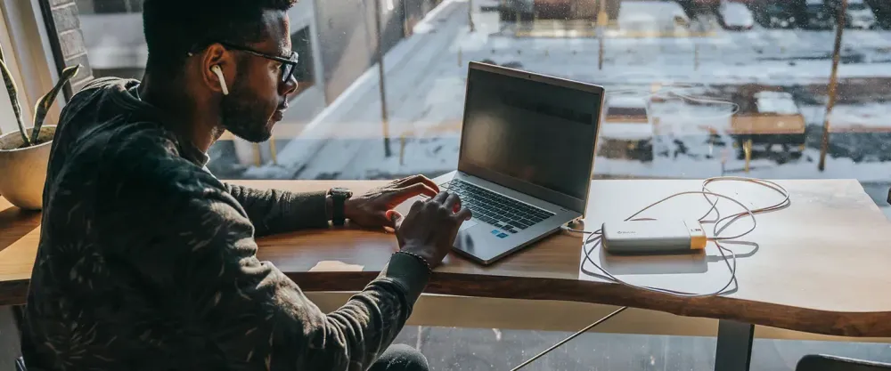 Man working in cafe with laptop plugged into a BioLite Charge Series portable charger